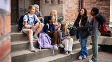 Skoleelever sitter på en kirketrapp. Foto: Den norske kirke.